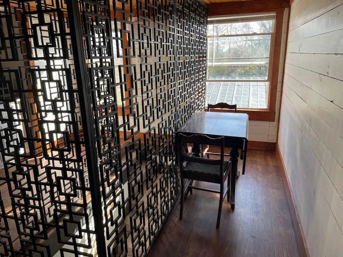 This interior image features a window with natural light streaming in, a dining table, and a decorative room divider. The window aspect subtly hints at indoor-outdoor transitions, and the mention of sunset views from the window connects thematically to enjoying the changing light throughout the day.